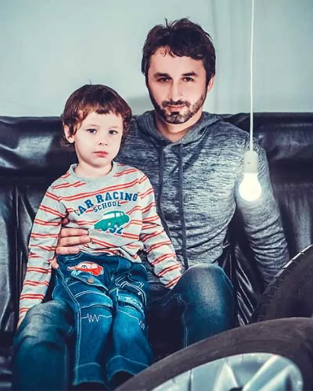 A father and his young son sitting together on a couch