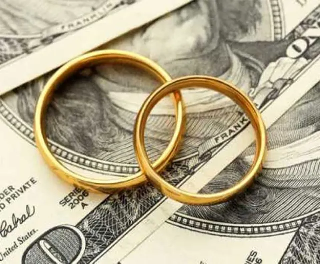 Two gold wedding rings resting on U.S. currency