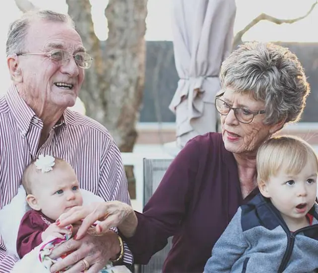 Grandparents smiling with two young grandchildren